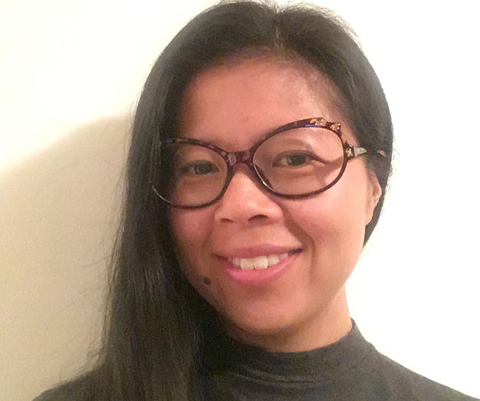 A woman with brown hair and glasses smiling.