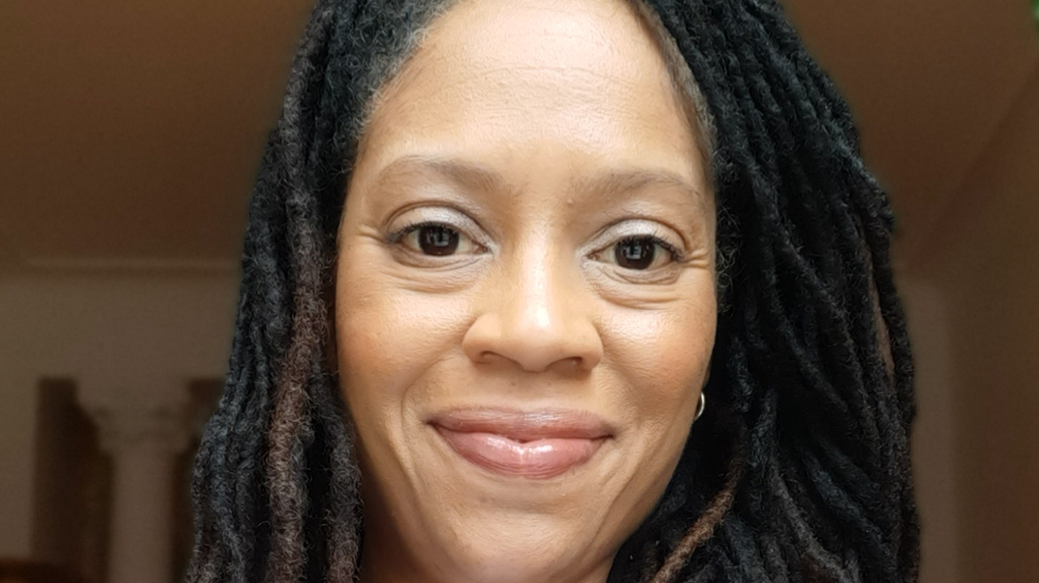 A woman with brown eyes and long braids smiling