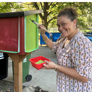 une femme peint une boîte en bois en plein air